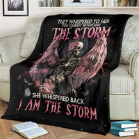 Black skeleton rose wings blanket with pink lettering, draped over light striped armchair
