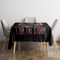 Black tablecloth with pink 'I AM THE STORM' text on dining table between gray chairs