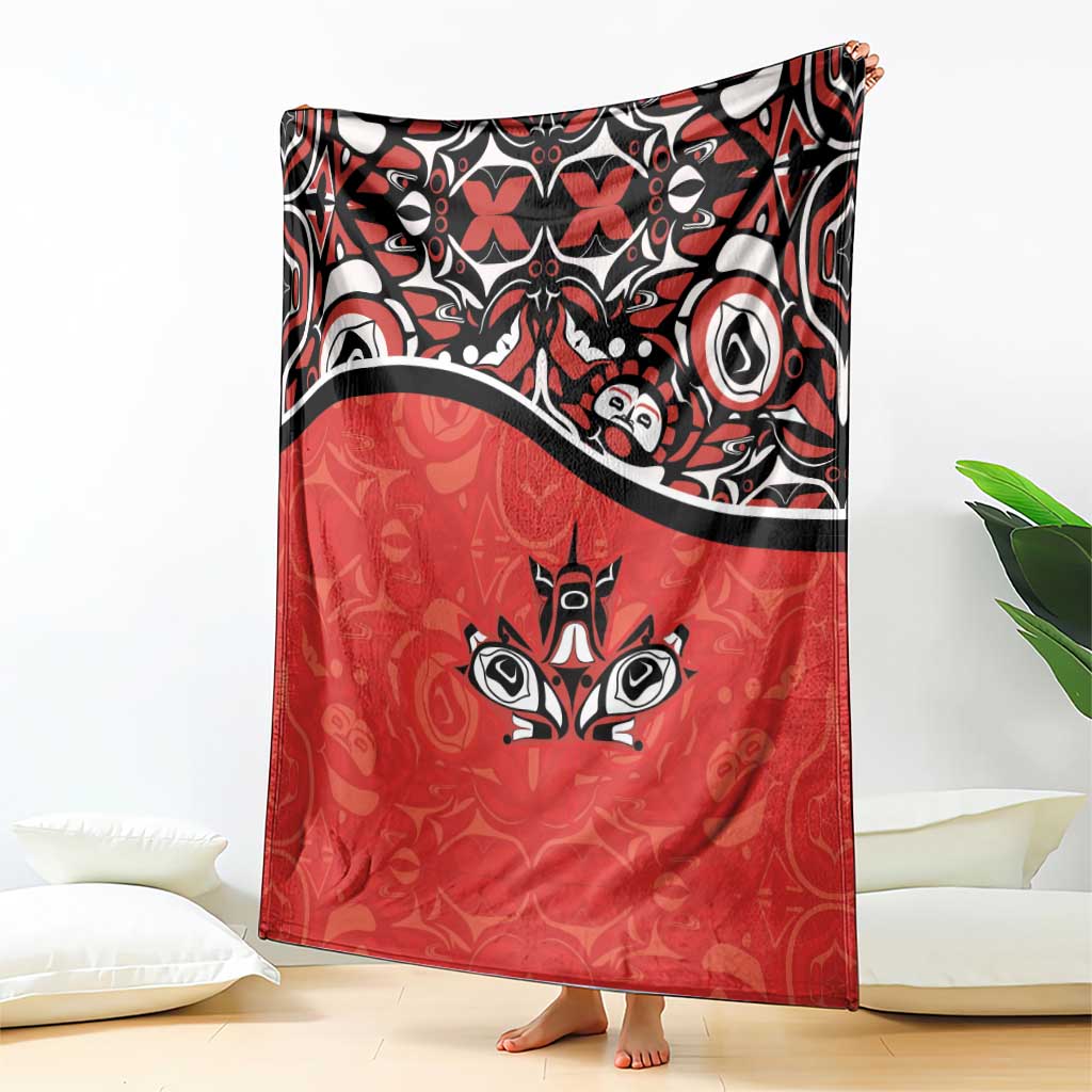Red blanket with bold black-and-white patterned top and centered maple leaf art