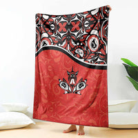 Red blanket with bold black-and-white patterned top and centered maple leaf art
