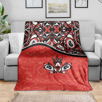 Red throw blanket draped over sofa, featuring black-and-white maple leaf tattoo