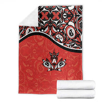 Red blanket folded with black-and-white patterned panel and maple leaf tattoo