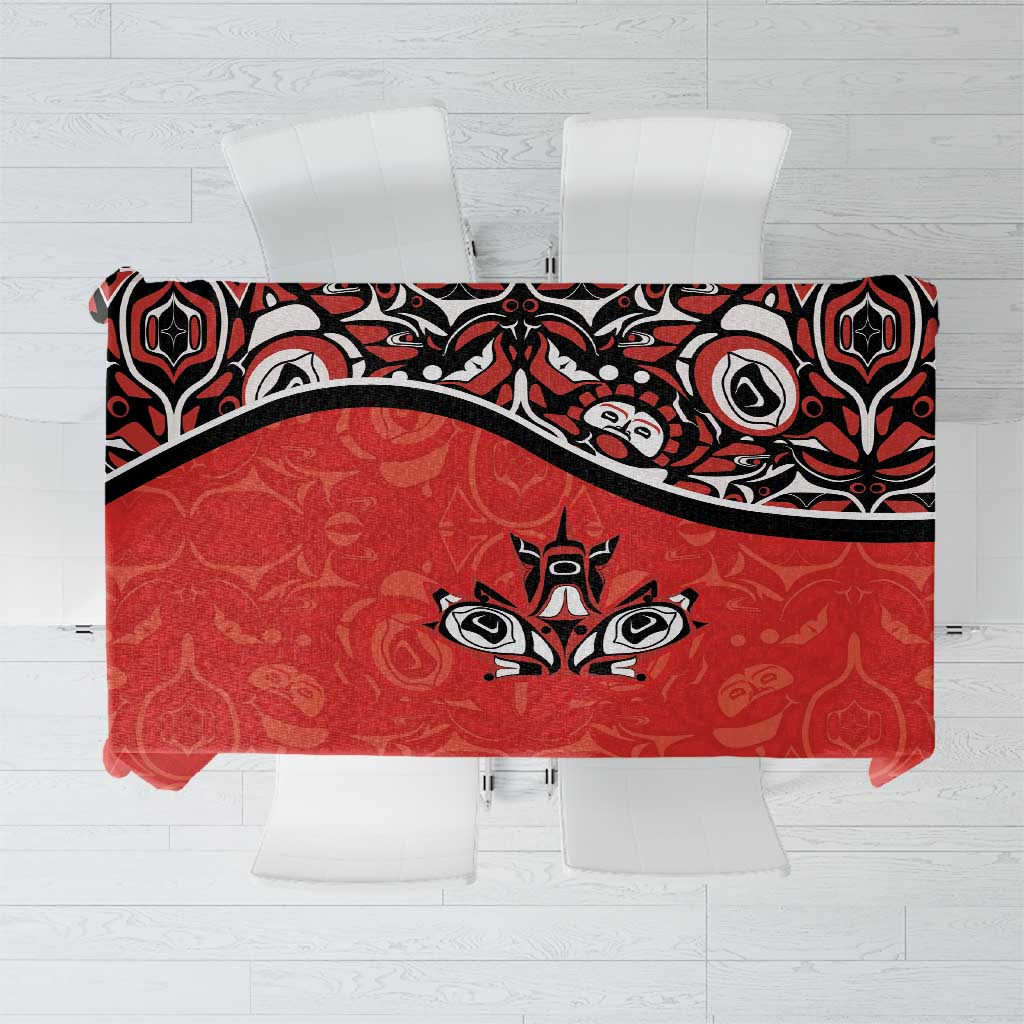 Red tablecloth with black Haida-style tattoo graphics and maple leaf motifs, flat lay