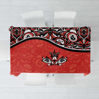 Red tablecloth with black Haida-style tattoo graphics and maple leaf motifs, flat lay