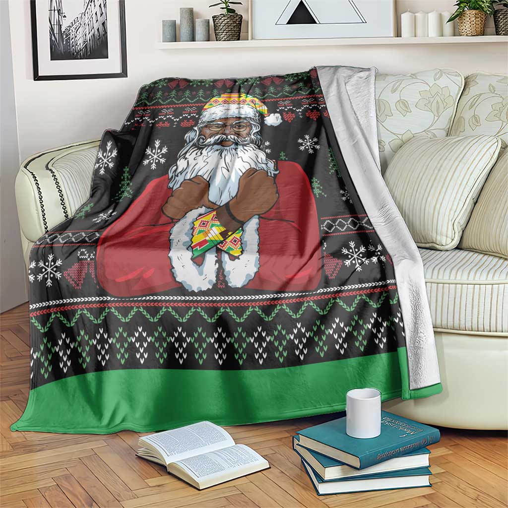 Black Christmas blanket with Santa in red robe and patterned hat, green border; draped on sofa.
