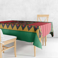 Corner view of red and green Christmas tablecloth with patterned edge and drape.