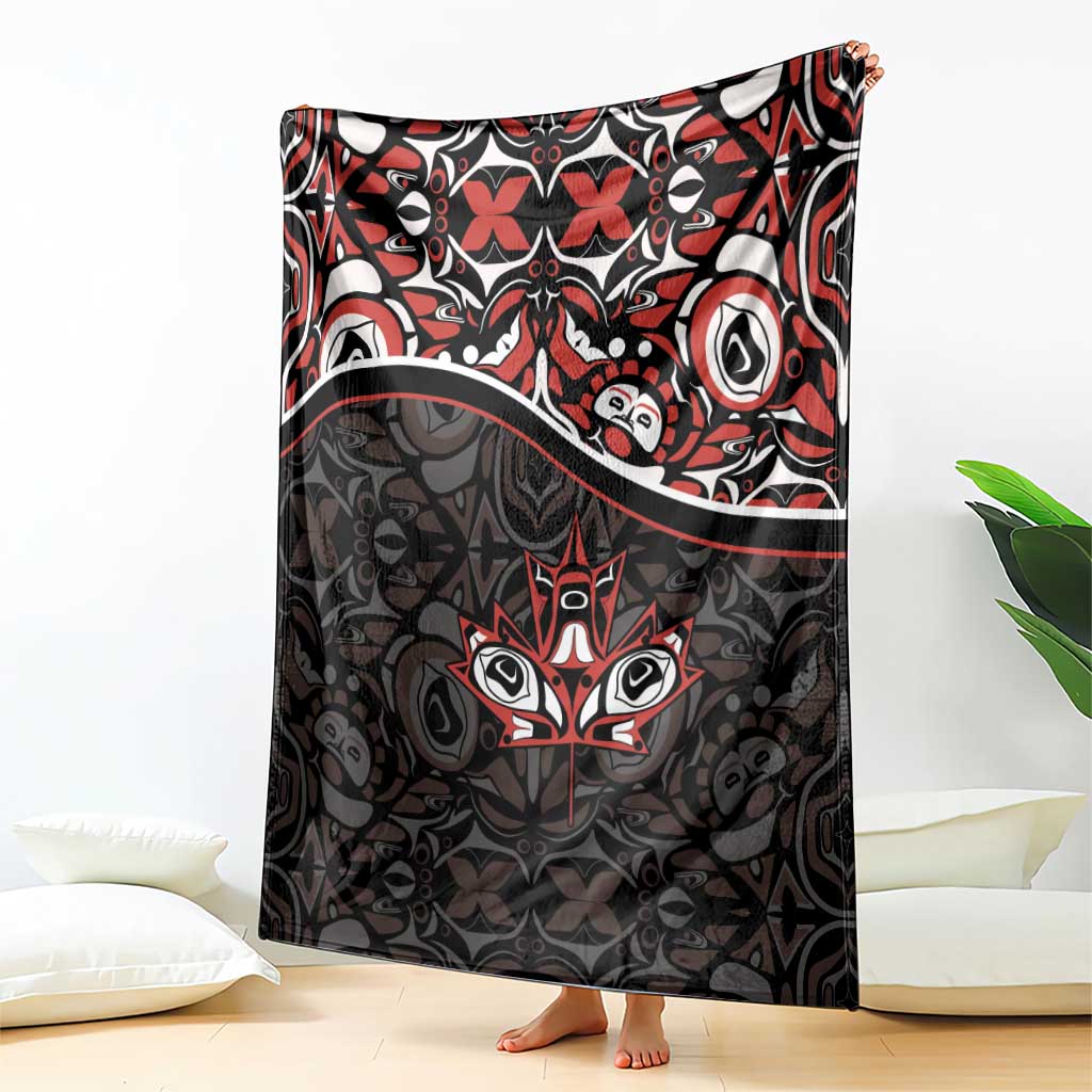 Black blanket standing on floor with red and white Haida-style tribal pattern and maple leaf motif