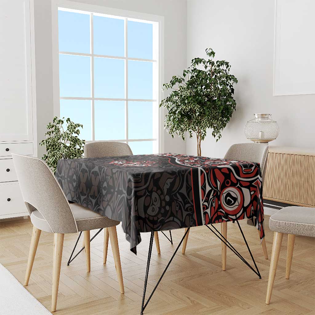 Black tablecloth featuring red and white Haida-style maple leaf tattoo motif on dining table