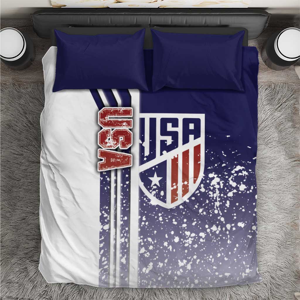 Flat-lay bedding set showing USA shield, speckled blue field, and two blue pillowcases