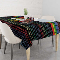 Black rectangular tablecloth with colorful design, placed on a dining table with place settings.