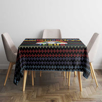Black square tablecloth with multicolor holiday motif pattern across the top.