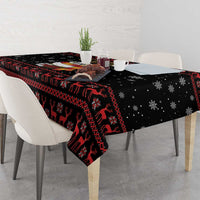 Black Christmas tablecloth draped over table with reindeer, snowflakes and red trim.