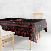 Black Christmas tablecloth with reindeer motifs and red geometric border on table edge.