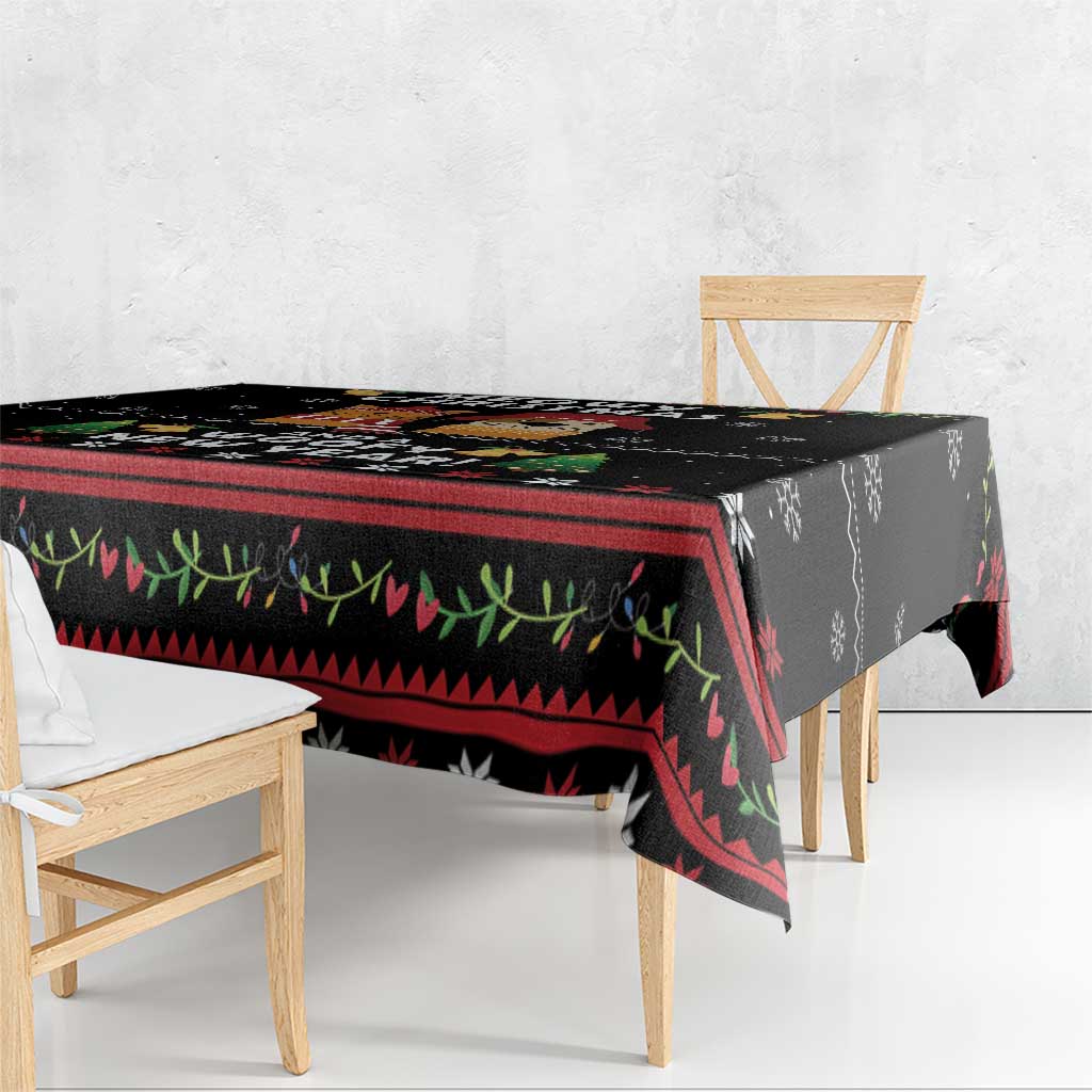 Black tablecloth with red, green, and white geometric border; overhang on table edge