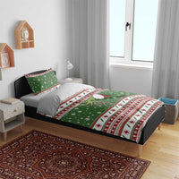 Green holiday bedding set on bed with duvet cover and pillowcases; snowflakes and red crosses