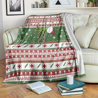Green Christmas blanket with red border stripes, white crosses, and stethoscope motif.