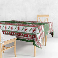 Green Christmas tablecloth over bench and table edge with red medical-cross border