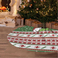 Round nurse-themed Christmas tree skirt in green and red with white fringe edge on wooden floor