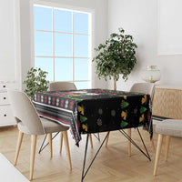 Black holiday tablecloth with festive icons and patterned border on a dining table