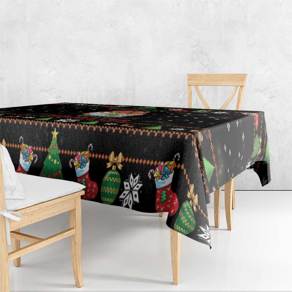 Black holiday tablecloth with colorful tree, sock, and star pattern along the edge