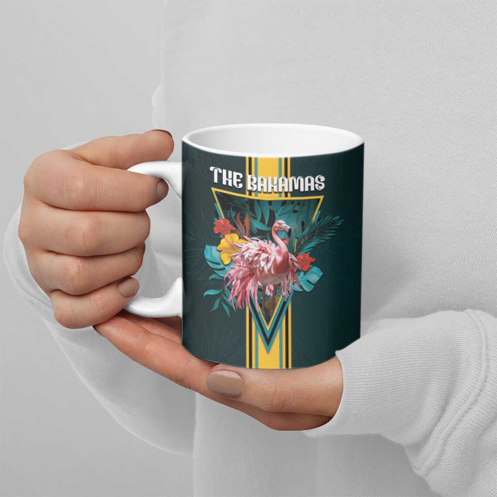 Dark teal ceramic mug held by hand with "THE BAHAMAS" flamingo tropical flowers