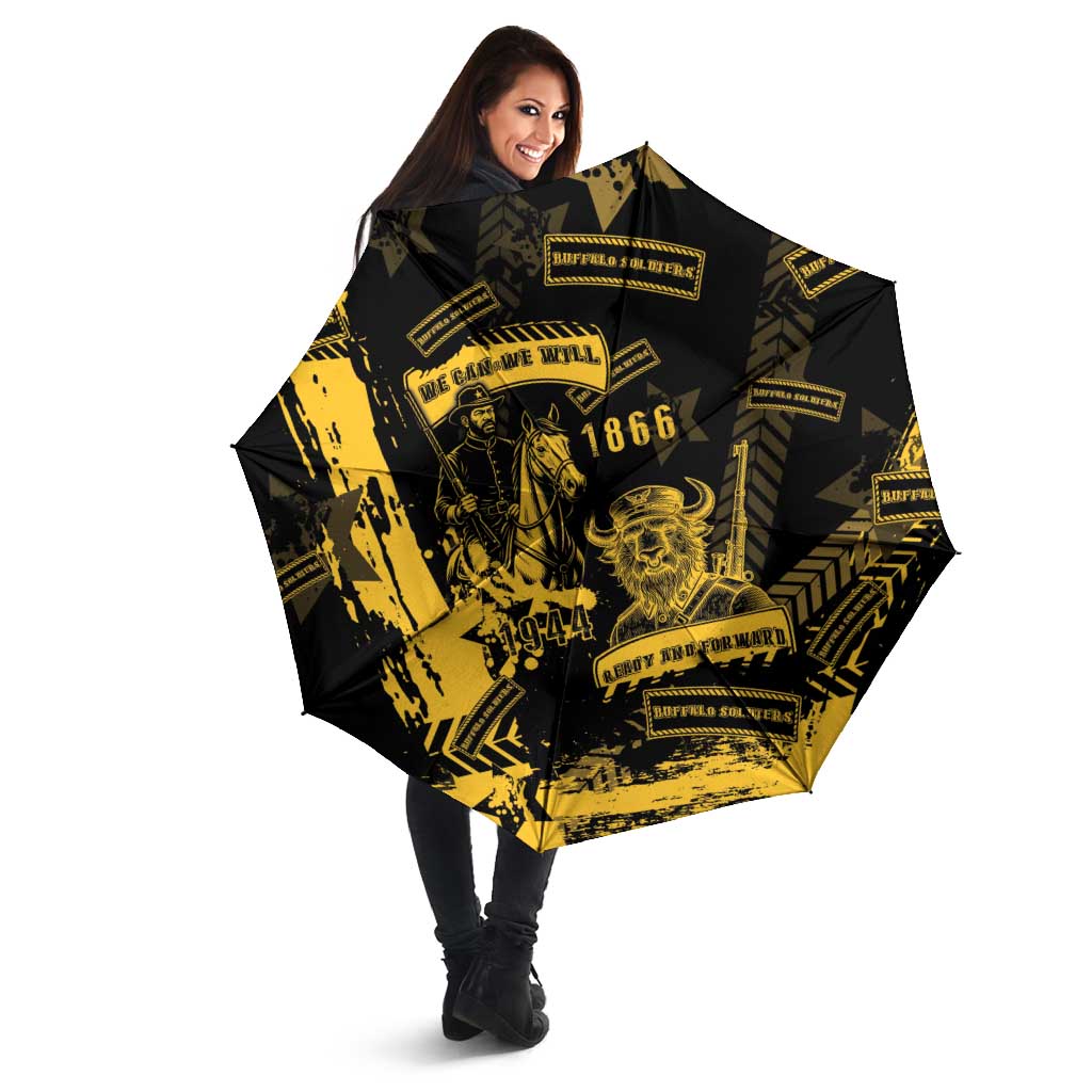 Black umbrella with yellow military graphic, held by person outdoors
