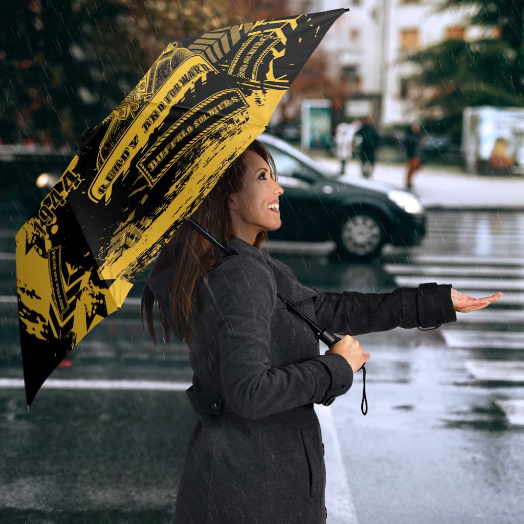 Black umbrella with bold yellow military graphic, held above shoulder