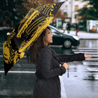 Black umbrella with bold yellow military graphic, held above shoulder