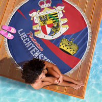 Round Liechtenstein beach blanket top view, blue red crest design and white tassel fringe