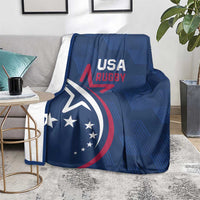 Blue USA Rugby blanket with eagle and stars, folded over a gray chair and rug.