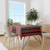 Rectangular tablecloth with multicolor geometric stripes and diamond borders, on a dining table.