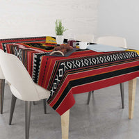 Patterned tablecloth with red, black, and striped geometric motifs draped over a dining table.
