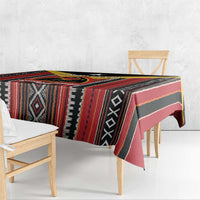 Geometric tablecloth with red, black, and pink-toned stripes and diamond accents on a bench.