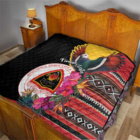Black quilt on bed with bird-and-floral graphic, red striped border, and national crest