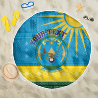 Round beach blanket on sand with Rwanda coat of arms emblem, blue and yellow pattern