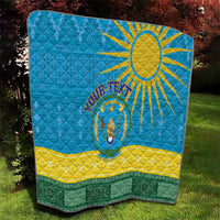 Blue quilt blanket with sun and central emblem, yellow stripe and green patterned bottom
