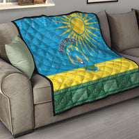 Blue quilt blanket on couch with sun and Rwanda emblem, yellow chevrons and green trim