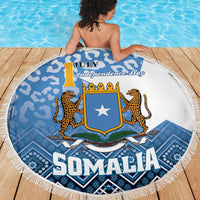 Round beach blanket in blue-and-white with Somalia crest, leopard figures, and fringed edge.