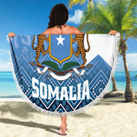 Round beach blanket held up, blue Somalia crest with star and leopard animals, fringed.
