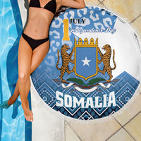 Round beach blanket close-up, blue camouflage pattern with SOMALIA crest and fringed border.