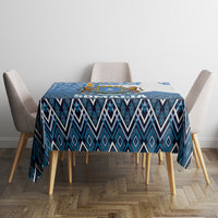 Blue geometric patterned tablecloth on a square dining table with chair edges visible