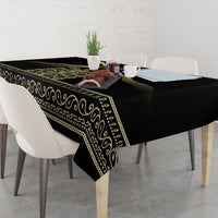 Black tablecloth draped on table with gold band trim and scroll border