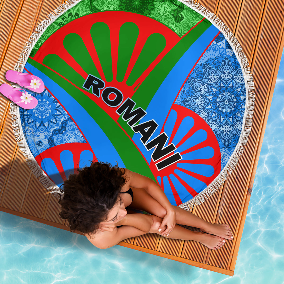 Round beach blanket with fringe, Romani text on green-red-blue rays, blue patterned sides