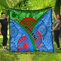 Romani patterned quilt spread outdoors: green top band and blue panels with red wheel motifs