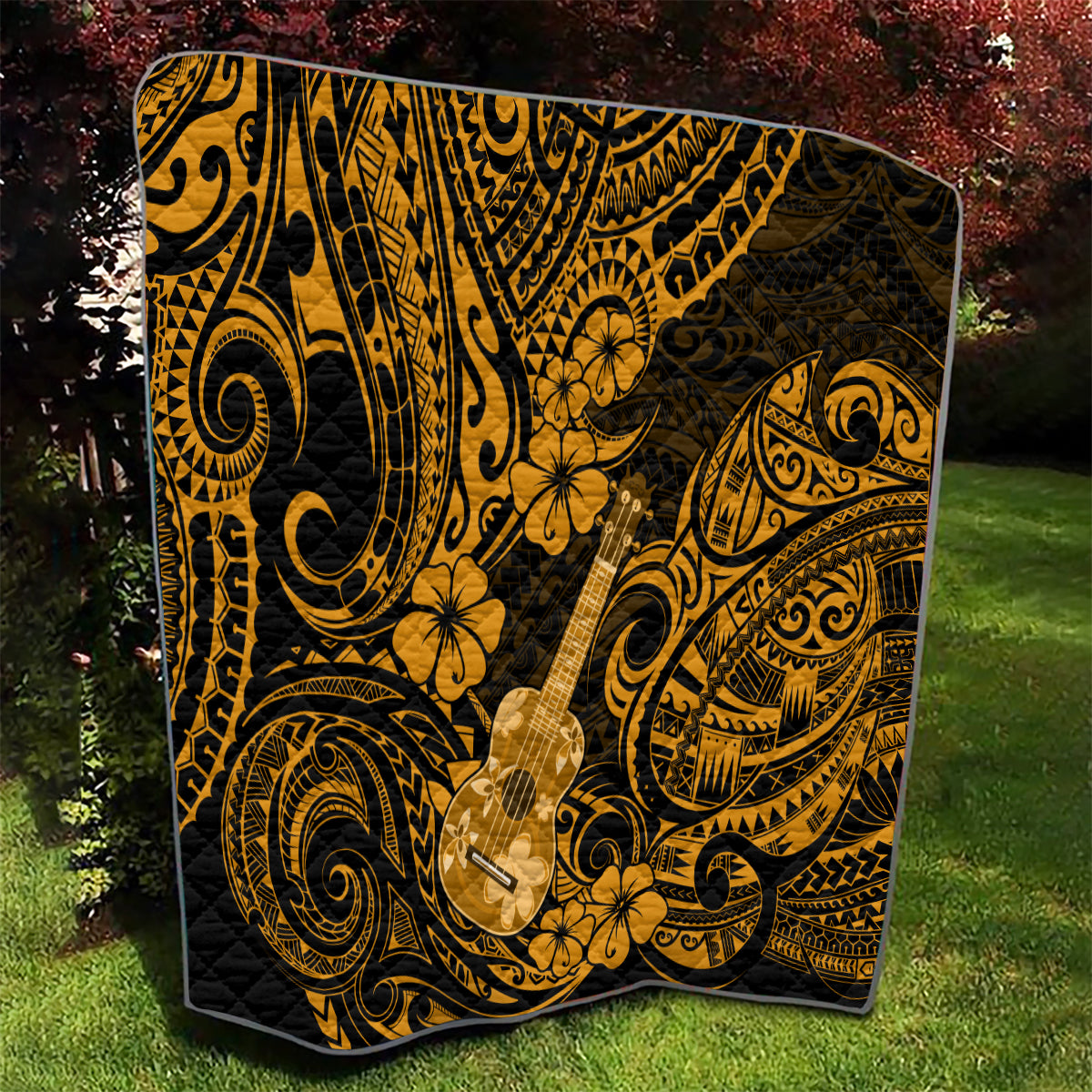 Black and gold ukulele-themed quilt featuring Polynesian scrollwork and flower motifs, spread
