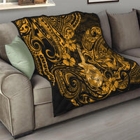 Gold and black ukulele quilt blanket with Polynesian swirl patterns and floral accents on sofa