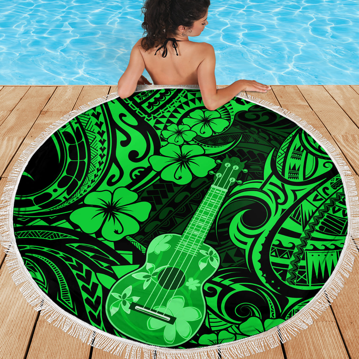 Round green Polynesian-pattern beach blanket with fringed edge and guitar motif.
