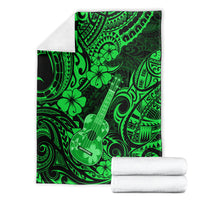 Green ukulele blanket with Polynesian pattern, shown folded with white towels