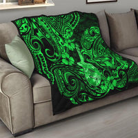 Green Polynesian pattern quilt blanket with ukulele and clover motifs on sofa