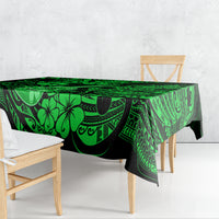 Green Polynesian-pattern tablecloth draped over table with hibiscus and swirling motifs